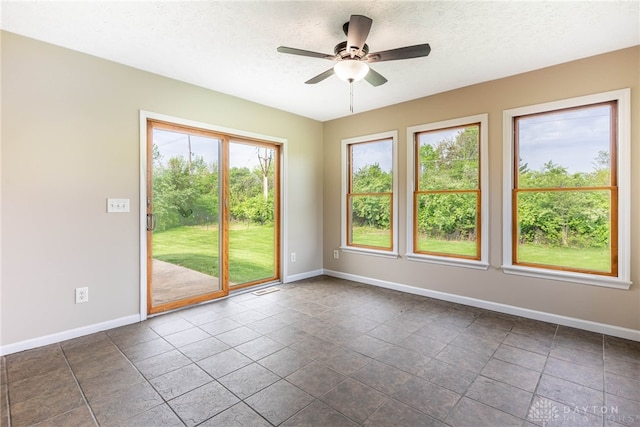 spare room with baseboards, a ceiling fan, and a textured ceiling