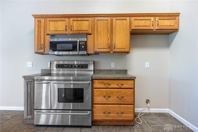 kitchen featuring baseboards, brown cabinetry, and stainless steel appliances