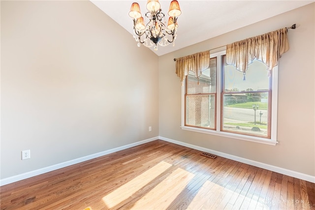 unfurnished room featuring baseboards, a chandelier, a wealth of natural light, and vaulted ceiling