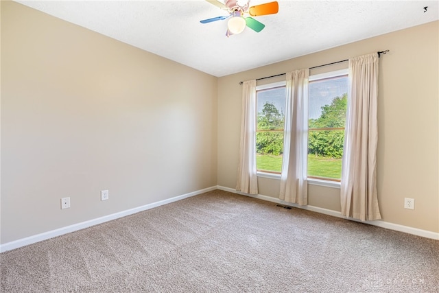 empty room with carpet flooring, baseboards, visible vents, and ceiling fan