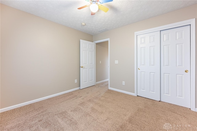 unfurnished bedroom featuring a textured ceiling, baseboards, light carpet, and a closet
