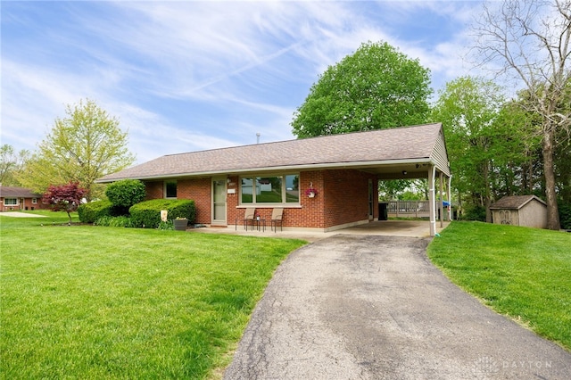 2661 Powhattan Pl, Dayton, OH 45420 - ranch-style home with a storage unit, brick siding, a front lawn, and aphalt driveway