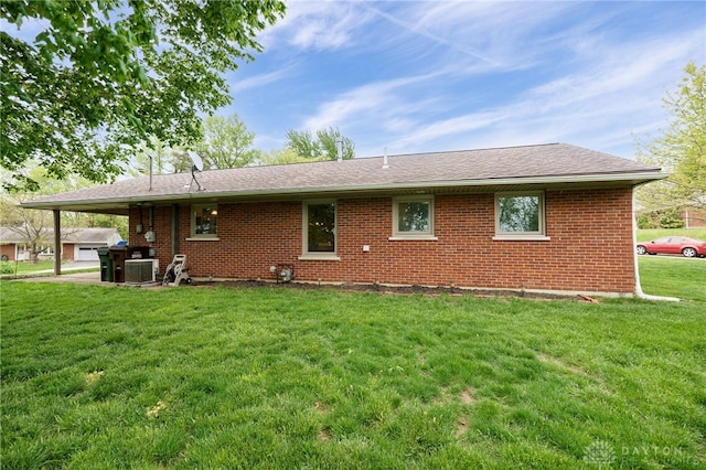 2661 Powhattan Pl, Dayton, OH 45420 - back of property featuring brick siding, a lawn, central air condition unit, and roof with shingles