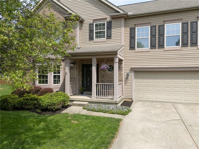 traditional-style house with a porch, a garage, brick siding, a front lawn, and concrete driveway