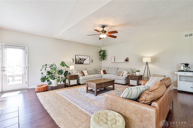living room featuring ceiling fan, a textured ceiling, baseboards, dark wood-type flooring, and visible vents