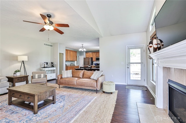 living room featuring a fireplace, ceiling fan with notable chandelier, baseboards, wood finished floors, and visible vents