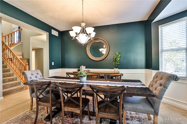 dining space with carpet floors, a notable chandelier, wainscoting, and stairway