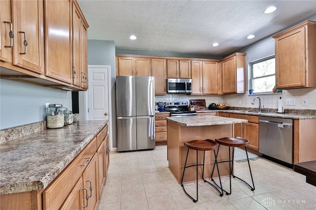 kitchen featuring a kitchen bar, recessed lighting, tasteful backsplash, a sink, and appliances with stainless steel finishes