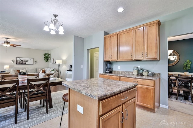 kitchen with light tile patterned floors, a kitchen island, a textured ceiling, and open floor plan