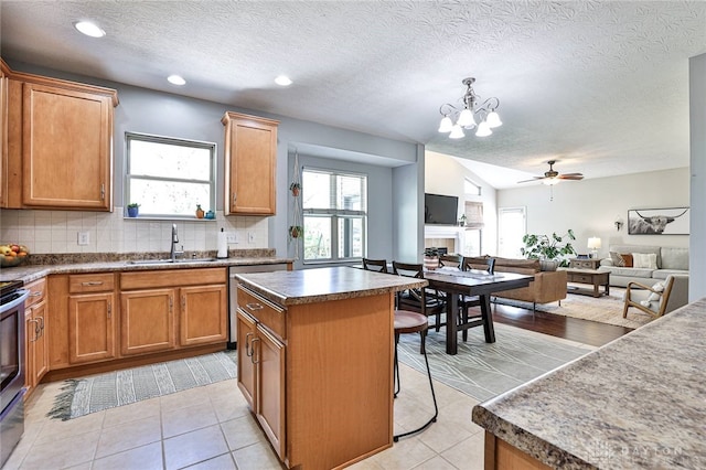kitchen with decorative backsplash, a center island, a sink, ceiling fan with notable chandelier, and open floor plan