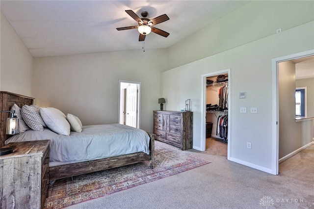 bedroom with light colored carpet, vaulted ceiling, baseboards, a closet, and a spacious closet