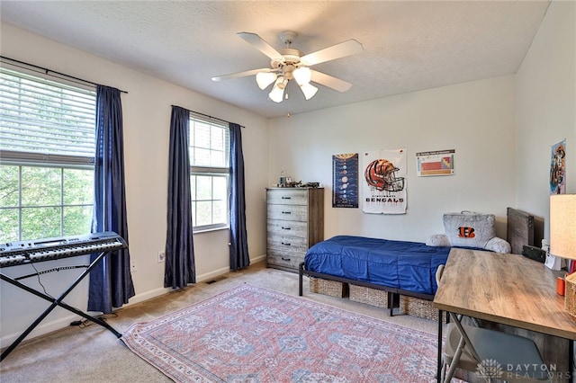 bedroom with a ceiling fan, a textured ceiling, visible vents, carpet floors, and baseboards