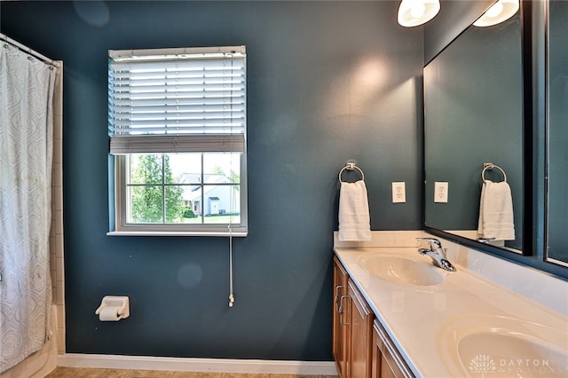 bathroom with double vanity, a sink, baseboards, and curtained shower