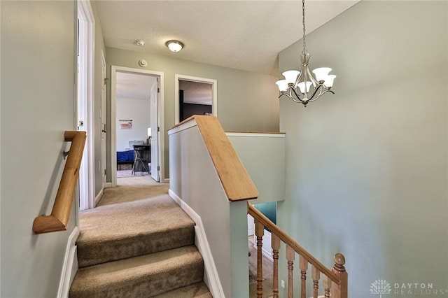 stairway with carpet floors, baseboards, and an inviting chandelier