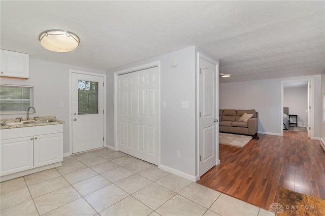 12 N Water St, Lebanon, OH 45036 - kitchen with a sink, white cabinetry, baseboards, light wood-type flooring, and light stone counters