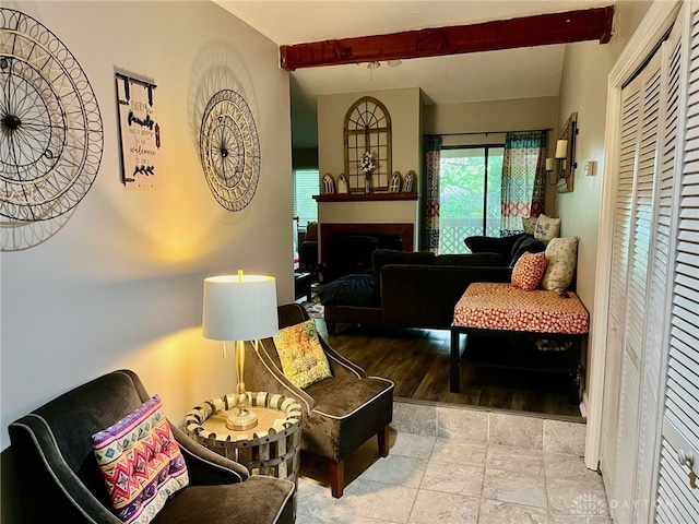 living area with a fireplace, stone finish floor, and beamed ceiling