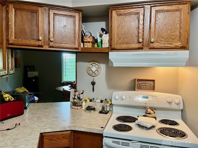 kitchen with light countertops, brown cabinets, range hood, and electric stove