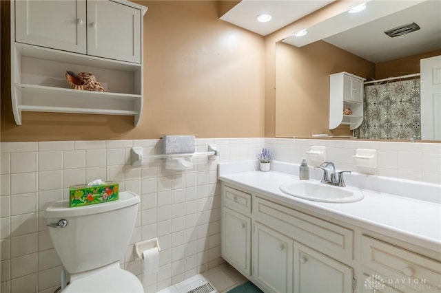 bathroom featuring wainscoting, vanity, toilet, tile walls, and visible vents