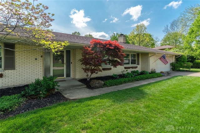 view of front of house featuring brick siding, an attached garage, a chimney, and a front lawn