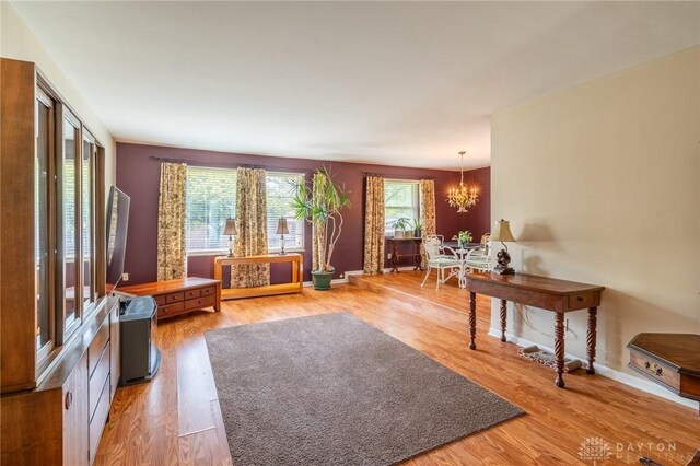 living room with an inviting chandelier, light wood-style floors, and baseboards
