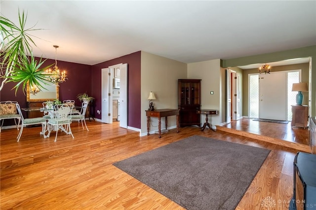 living area featuring baseboards, light wood finished floors, and a notable chandelier