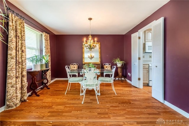 dining room with light wood-style floors, baseboards, and a chandelier