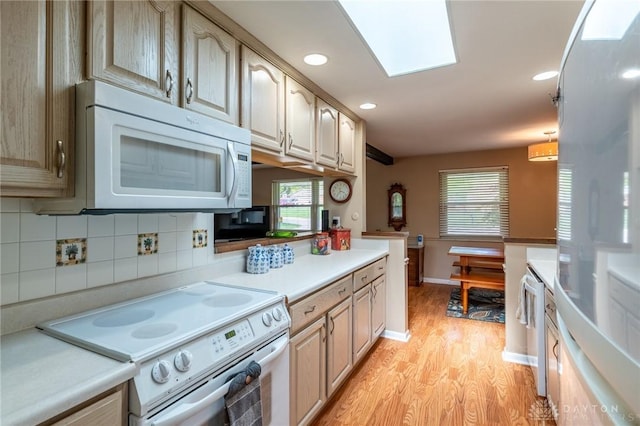kitchen with tasteful backsplash, light countertops, light wood finished floors, recessed lighting, and white appliances