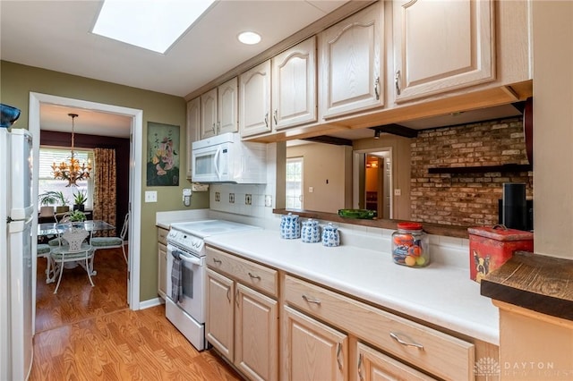kitchen with light brown cabinets, white appliances, light countertops, a chandelier, and light wood-style flooring