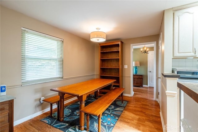 dining room with baseboards, a notable chandelier, and light wood-type flooring