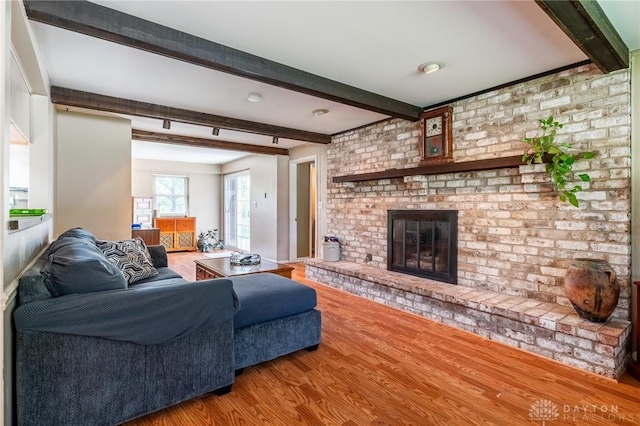 living room with wood finished floors, a fireplace, and beamed ceiling