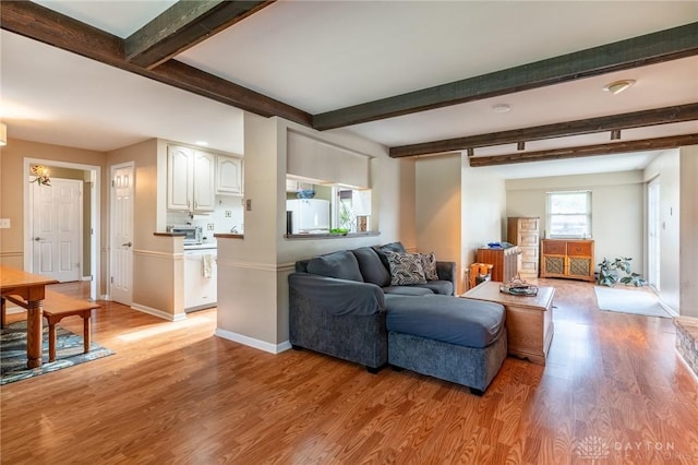 living area with baseboards, light wood-type flooring, and beam ceiling