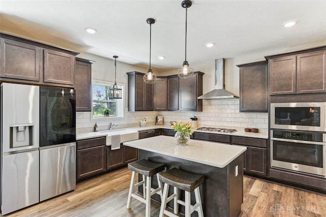 2187 Hamilton Rd, Lebanon, OH 45036 - kitchen with dark brown cabinetry, wall chimney exhaust hood, a sink, light wood-style flooring, and stainless steel appliances