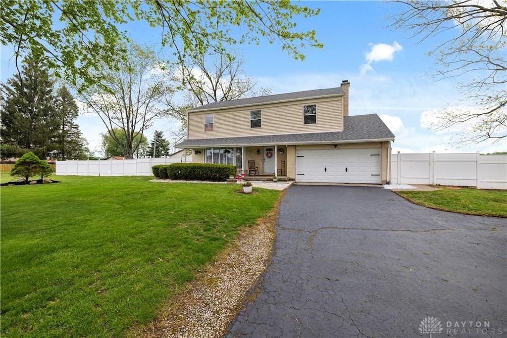traditional-style home with fence, a front lawn, a garage, a chimney, and driveway