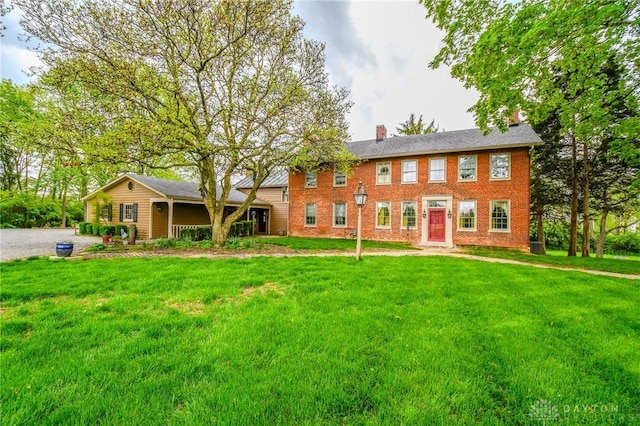 rear view of house with a yard, a chimney, and brick siding