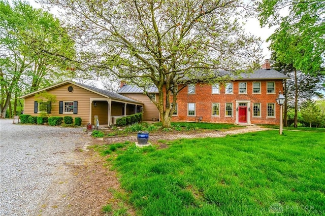 colonial-style house with a chimney and a front lawn