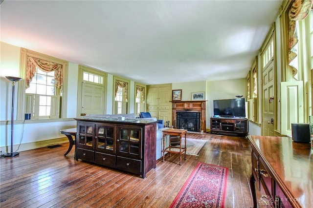 living area with baseboards, a fireplace, visible vents, and dark wood-style floors