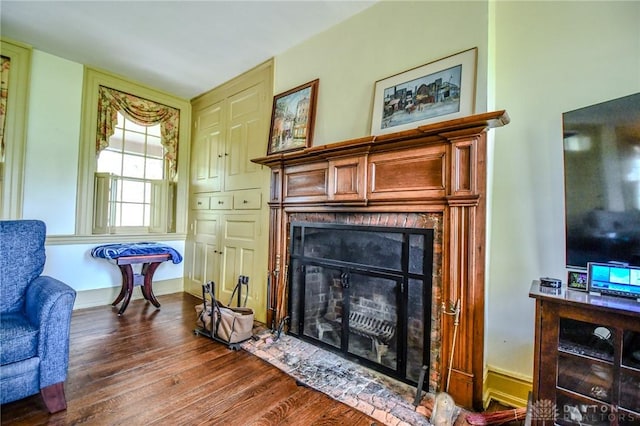 sitting room with dark wood-style flooring and a fireplace with flush hearth