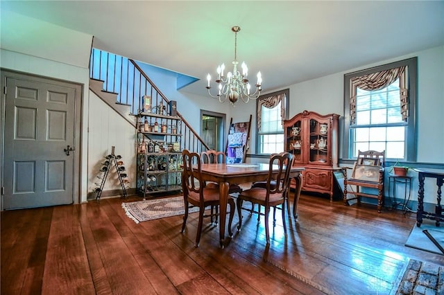 dining space featuring hardwood / wood-style flooring, stairs, a notable chandelier, and plenty of natural light