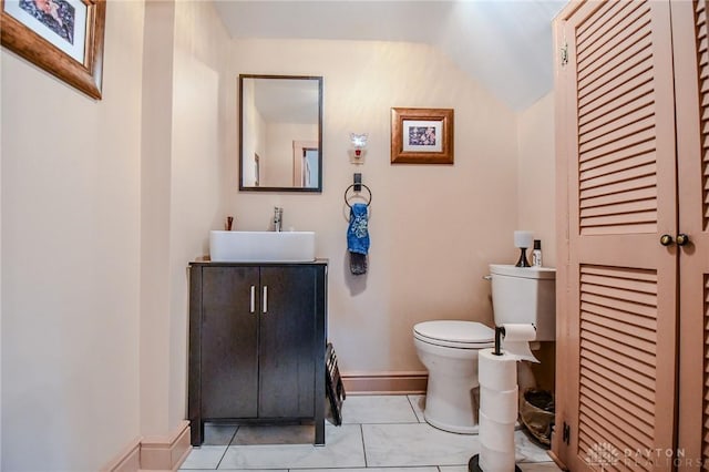 bathroom with vanity, toilet, baseboards, and lofted ceiling