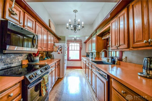 2100 Wagner Trace Dr, Beavercreek, OH 45431 - kitchen with freestanding refrigerator, a notable chandelier, a sink, dishwashing machine, and electric range