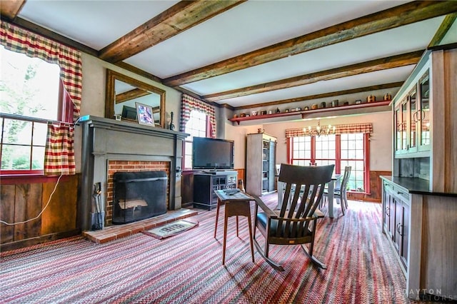 carpeted dining room with beamed ceiling, a brick fireplace, and an inviting chandelier