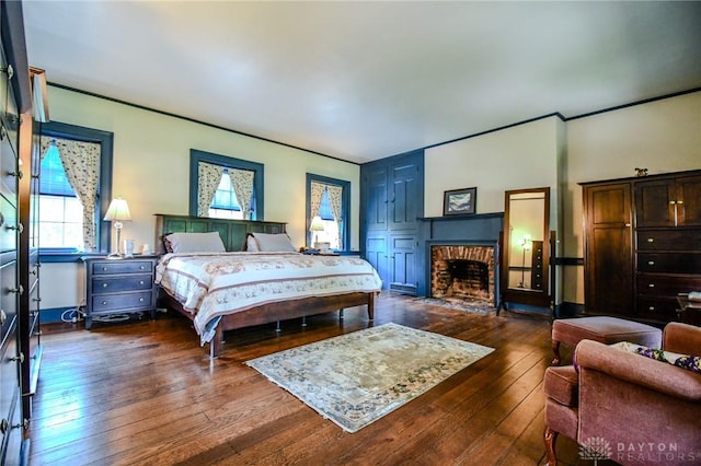 bedroom featuring crown molding, a fireplace, and dark wood-style floors