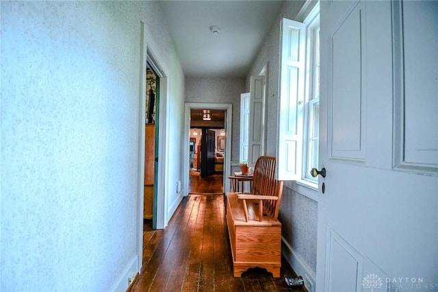 hall with baseboards, wallpapered walls, and dark wood-type flooring