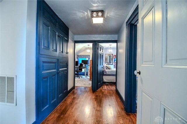 hall with dark wood-type flooring, baseboards, and visible vents