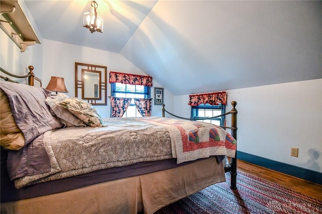 bedroom with vaulted ceiling, baseboards, and wood finished floors