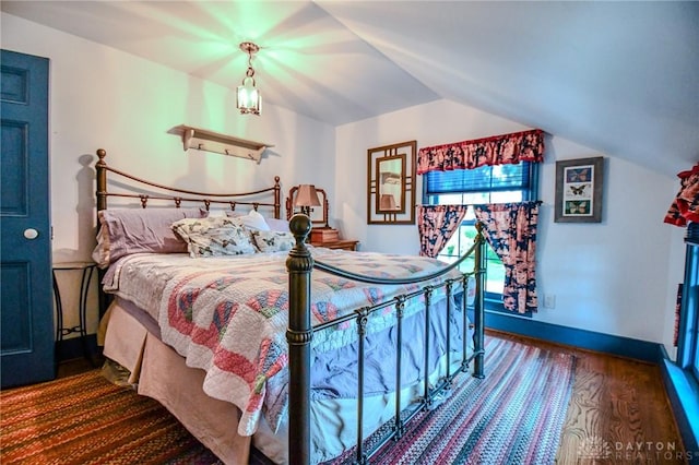 bedroom featuring lofted ceiling, baseboards, and dark wood finished floors
