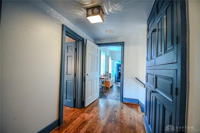 hall featuring dark wood-type flooring and baseboards