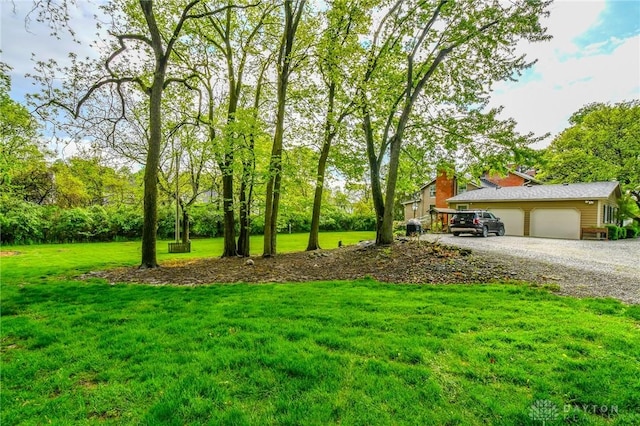 view of yard with an attached garage and gravel driveway