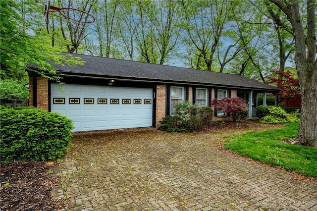 ranch-style house featuring brick siding, decorative driveway, and an attached garage