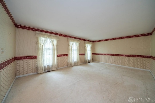 spare room featuring wallpapered walls, ornamental molding, and carpet